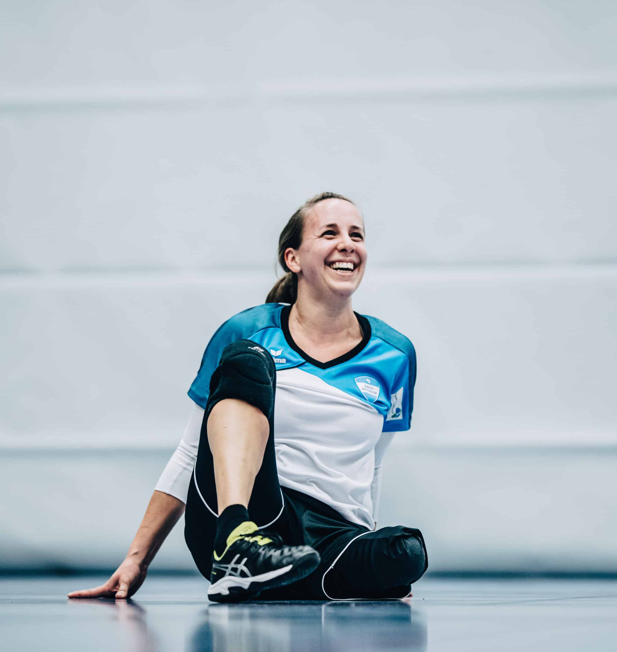 Salome sitzt auf einem Turnhallenboden während eines Volleyballspiels.